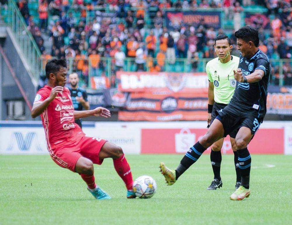 Dedik Setiawan saat berebut bola dengan pemain Persija Jakarta. (Instagram/aremafcofficial)