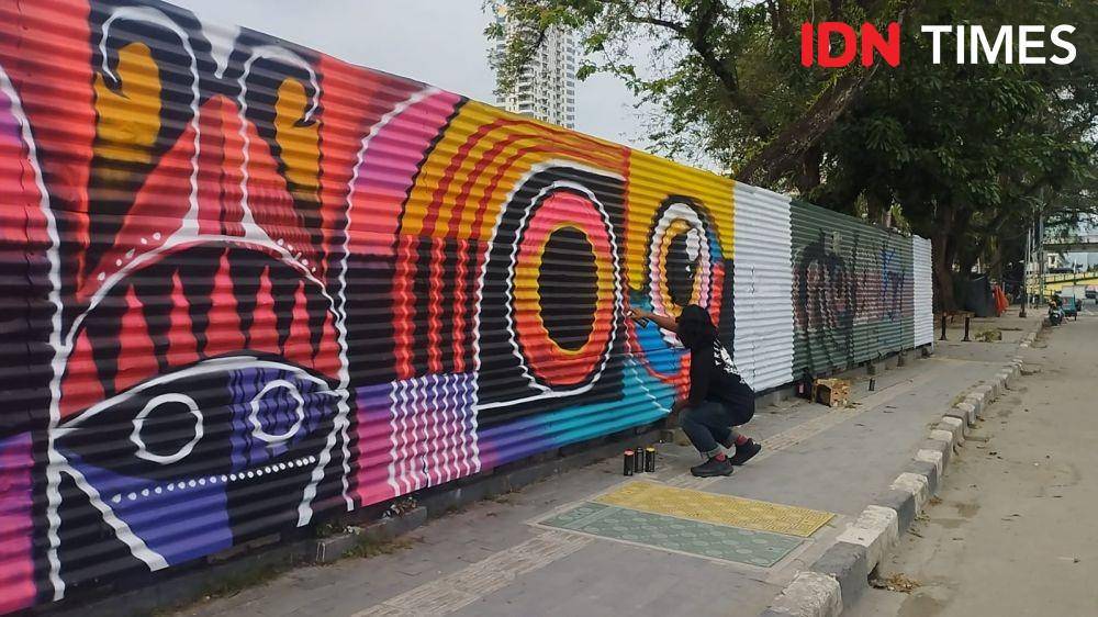 Seorang seniman sedang menggambar mural di kawasan revitalisasi Lapangan Merdeka Medan (IDN Times/Doni Hermawan)