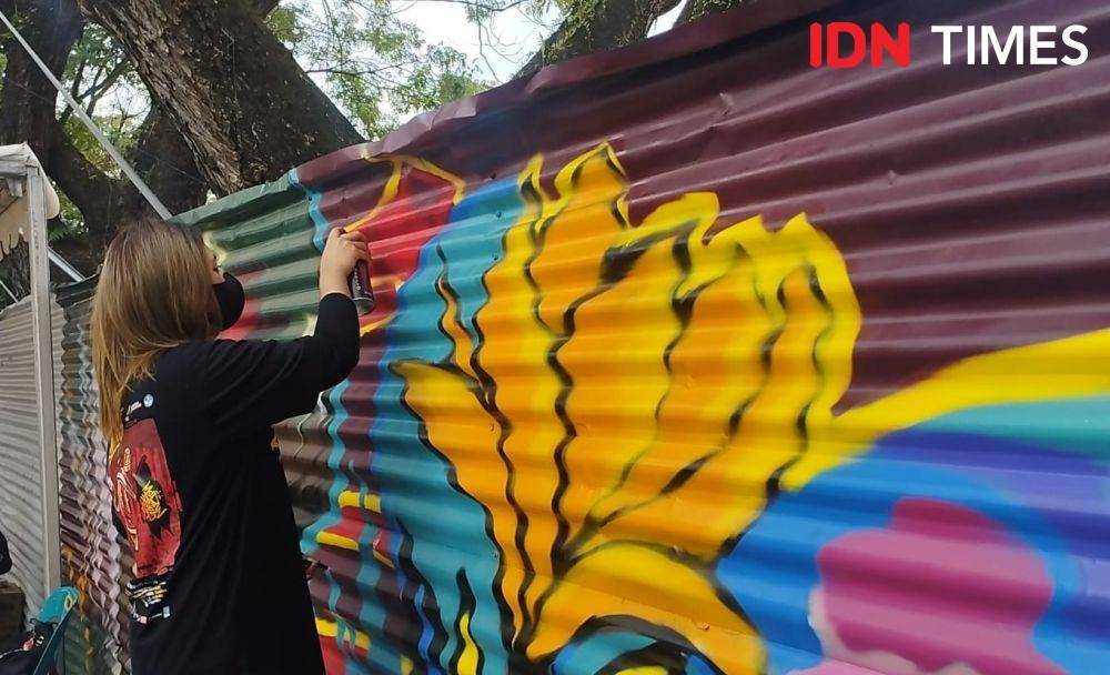Seorang seniman sedang menggambar mural di kawasan revitalisasi Lapangan Merdeka Medan (IDN Times/Doni Hermawan)