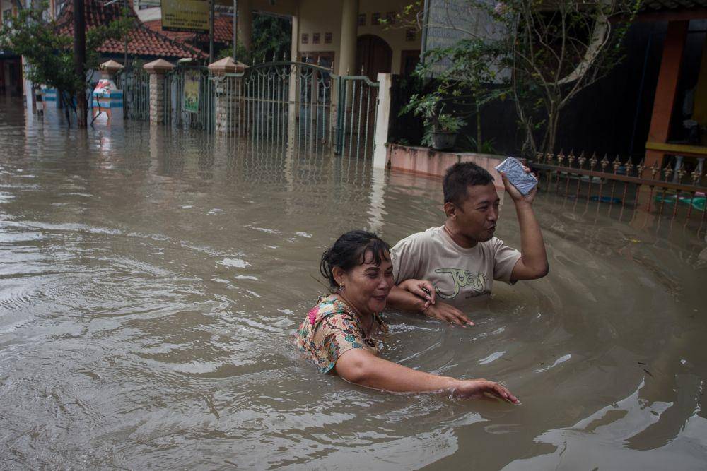 Warga melintasi genangan air yang merendam perkampunganya saat banjir di Kampung Joyotakan, Solo, Jawa Tengah, Jumat (17/2/2023). (ANTARA FOTO/Mohammad Ayudha)