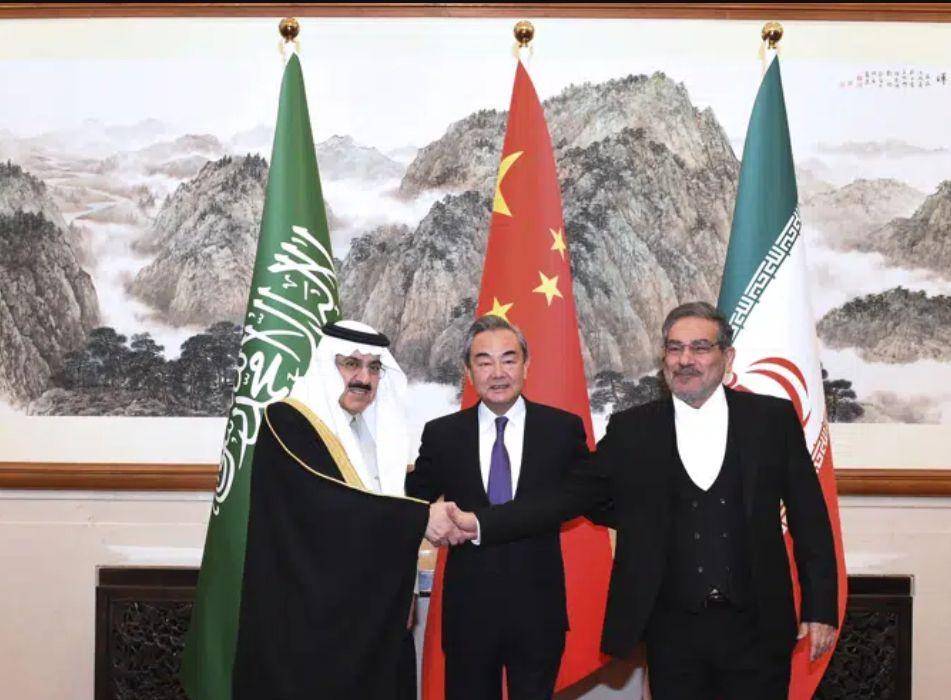 Sekretaris Dewan Keamanan Nasional Iran, Ali Shamkhani berjabat tangan dengan penasihat keamanan nasional Arab Saudi, Musaad bin Mohammed al-Aiban dalam pertemuan di Beijing bersama diplomat China Wang Yi. (Dok.AP News)