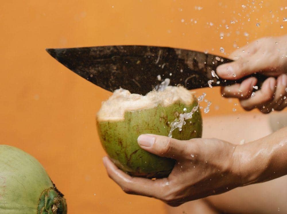 Ilustrasi air kelapa segar dalam gelas bening dengan potongan kelapa, minuman tropis yang tampak menyegarkan.