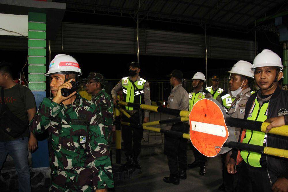 Anggota satuan pengamanan dan prajurit TNI berjaga di pintu masuk Kilang Minyak Putri Tujuh Pertamina RU II Dumai saat terjadi kebakaran akibat ledakan di area "gas compressor" Kilang Dumai, Riau, Sabtu (1/4/2023). (ANTARA FOTO/Aswaddy Hamid)