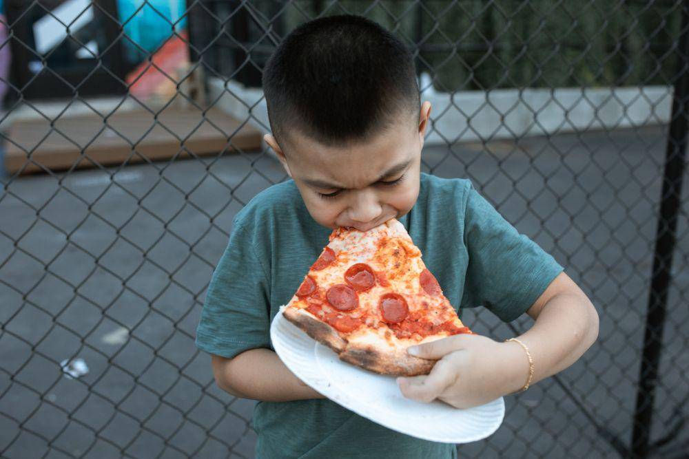 Potret bocah laki-laki memakan pizza (Pexels.com/RODNAE Productions)