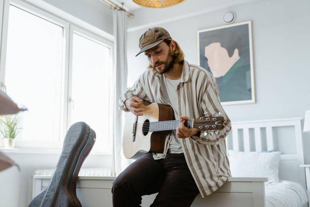 ilustrasi orang bermain gitar di rumah (pexels.com/MART PRODUCTION)