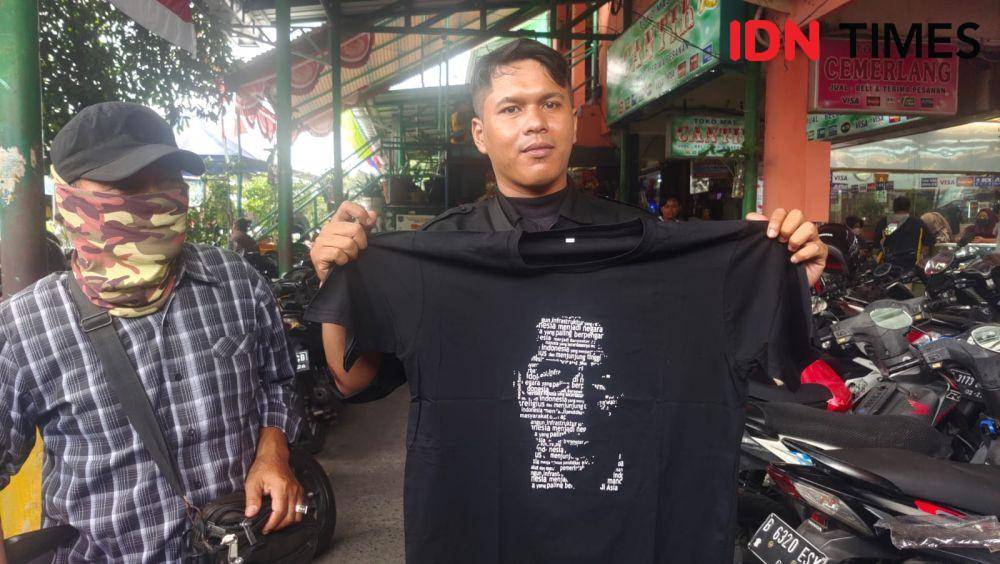 Salah seorang warga memperlihatkan kaus pemberian Presiden Joko Widodo saat mengunjungi Pasar Tugu, Kecamatan Cimanggis, Kota Depok. (IDNTimes/Dicky))