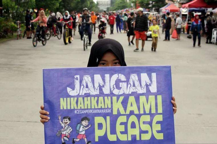 Seorang anak membawa poster saat aksi peringatan Hari Perempuan Internasional di Makassar, Sulawesi Selatan, Minggu (8/3/2020). (ANTARA FOTO/Arnas Padda)