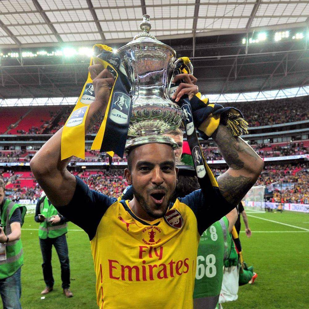 Mantan pemain Arsenal, Theo Walcott, sedang mengangkat trofi Piala FA bersama Arsenal setelah mengalahkan Aston Villa di final Piala FA 2015. (instagram.com/theowalcott)