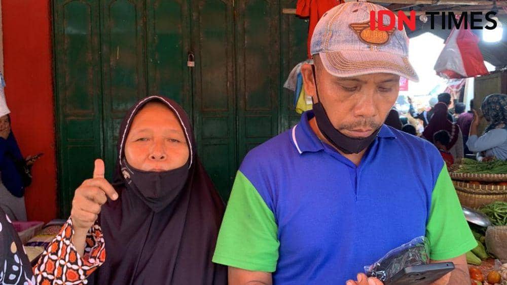 Sri (kiri), Pedagang kue di Pasar Natar mendapat bantuan uang dalam amplop dari Jokowi, Jumat (5/5/2023). (IDN Times/Rohmah Mustaurida).