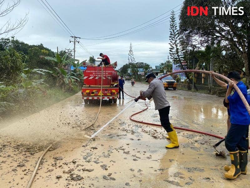 Kapolsek Sepaku AKP Kasiyono terjun langsung bersihkan jalan licin gunakan selang pemadam kebakaran (IDN Times/Ervan)