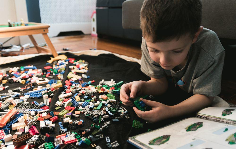 ilustrasi anak kecil yang sedang merakit Lego sesuai buku petunjuk (unsplash/kelly sikkema)