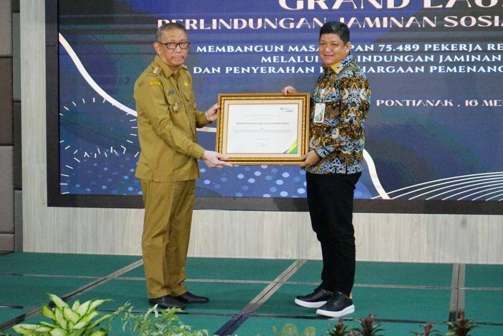 Direktur Kepesertaan BPJS Ketenagakerjaan Zainudin menyerahkan piagam penghargaan kepada Gubernur Kalbar Sutarmidji di Aula Pendopo Gubernur Kalbar, Selasa (16/5/2023). (Dok. BPJAMSOSTEK)