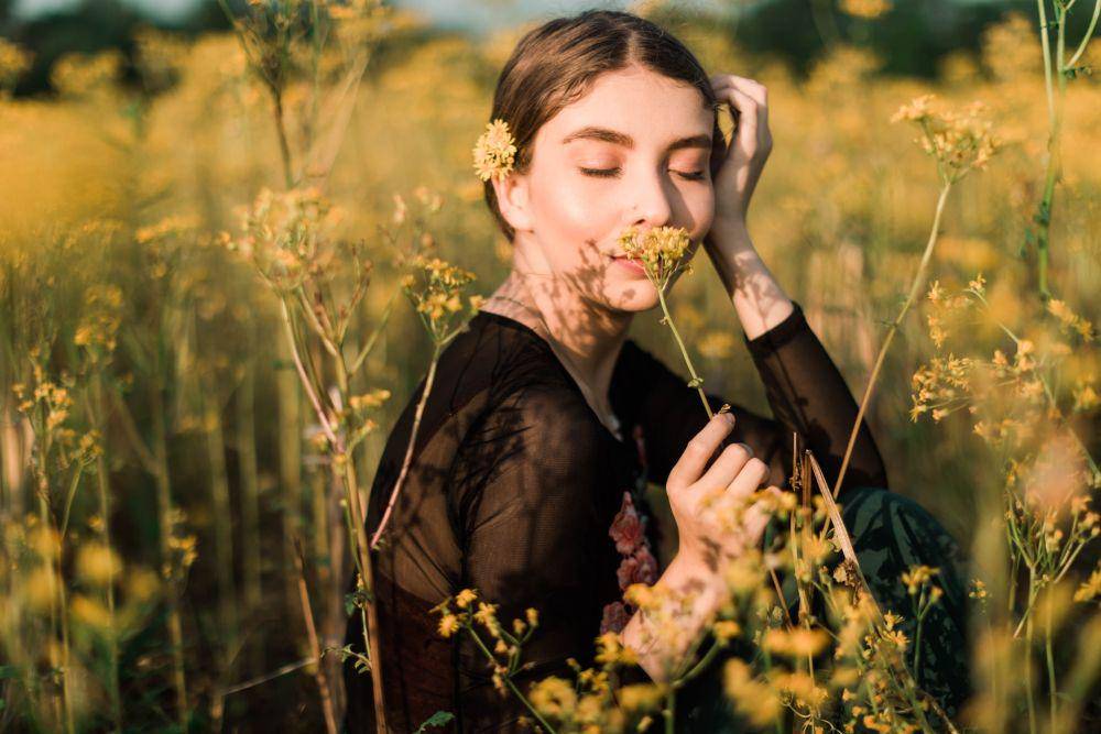 Seorang wanita yang mencium bunga (pexels.com/Leah Kelley)