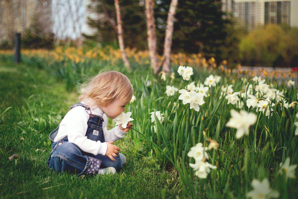 Seorang anak yang mencium aroma bunga (pexels.com/Tetyana Kovyrina)