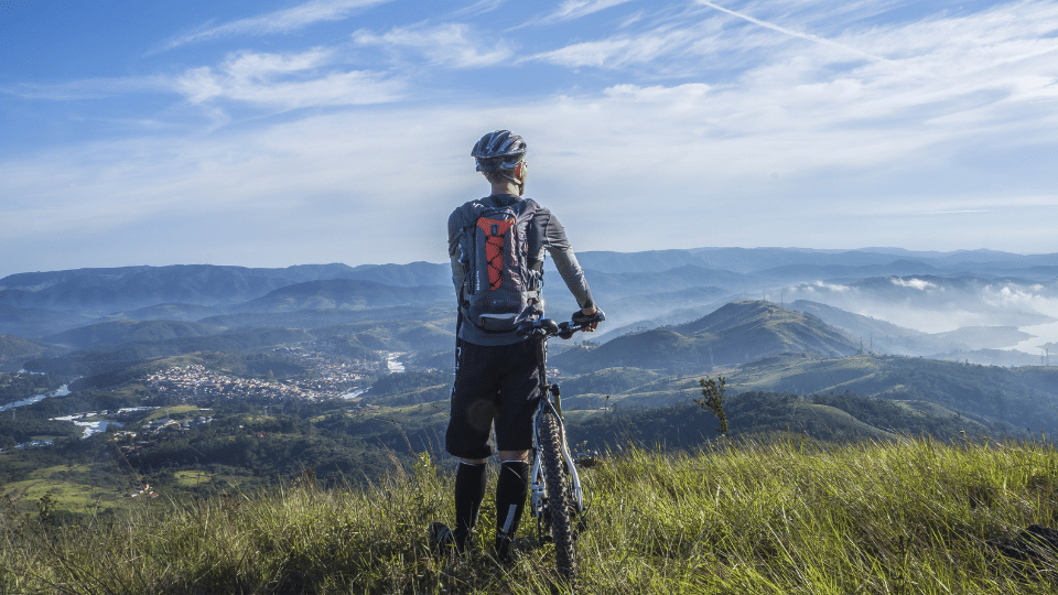 Seorang pria memegang sepeda di puncak gunung (pexels.com/Pixabay)