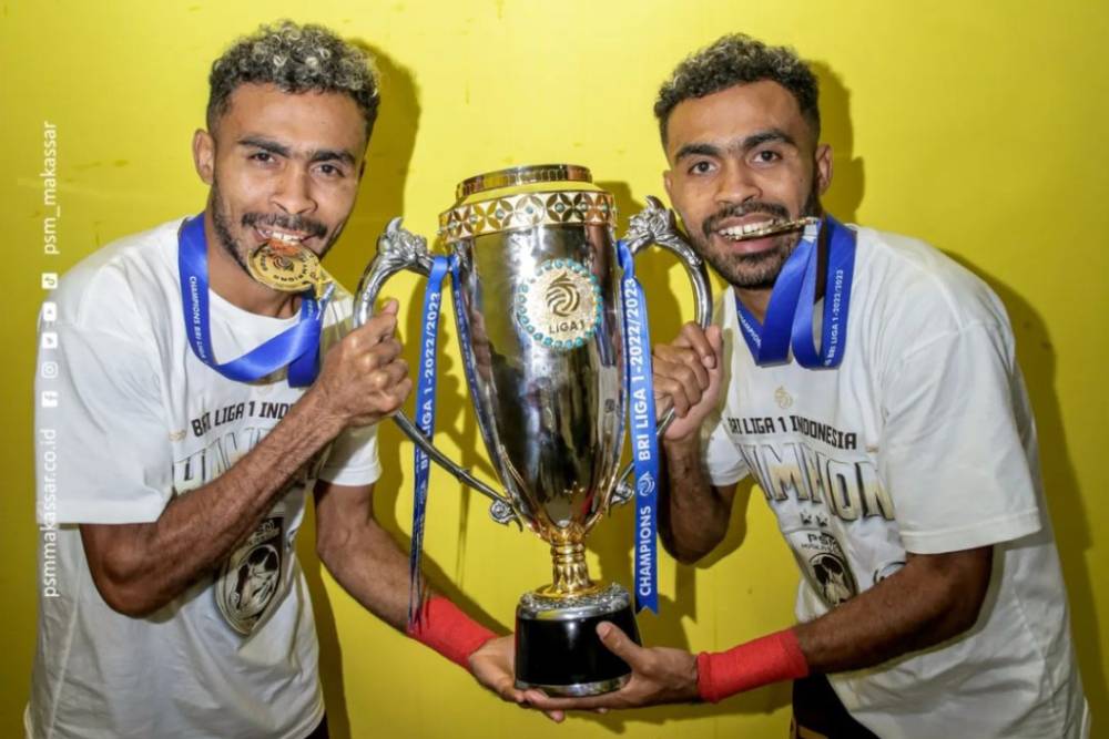 Pemain PSM Makassar, Yance Sayuri (kiri) dan Yakob Sayuri (kanan), berpose dengan trofi juara Liga 1 2022-23. (Instagram.com/psm_makassar)