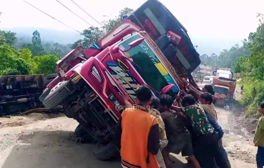 Warga membantu evakuasi truk yang terbalik di ruas jalan Dusun Batu Jomba, Desa Luat Lombang, Kecamatan Sipirok, Kabupaten Tapanuli Selatan. (Youtube: Bayo Buan)