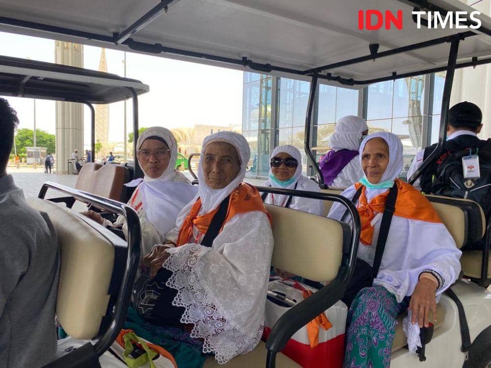 Beberapa jemaah haji lansia asal embarkasi Aceh duduk di kendaraan listrik mengenakan pakaian ihram putih dan syal oranye.