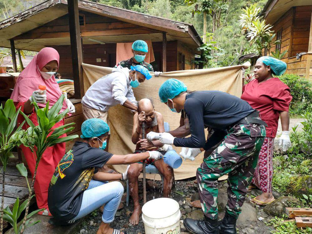 Personel Pos Tsinga Satgas Yonif R 631/Atg bersama tim medis Puskesmas Tsinga memandikan salah satu lansia. (IDN Times/Istimewa)