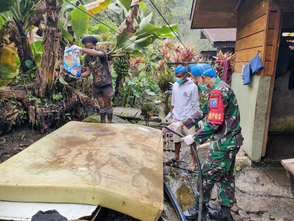 Personel Pos Tsinga Satgas Yonif R 631/Atg bersama tim medis Puskesmas Tsinga membersihkan kasur milik seorang lansia. (IDN Times/Istimewa)