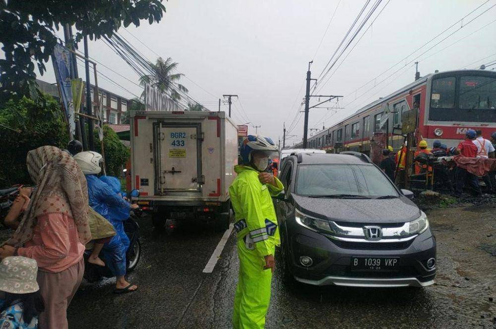 Anggota Satlantas Polres Metro Depok membantu pengaturan lalu lintas di lokasi angkot tertemper KRL Bogor-Jakarta, Kecamatan Cipayung, Kota Depok. (Istimewa)