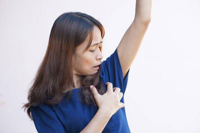 Seorang perempuan mengecek keringat di ketiaknya.