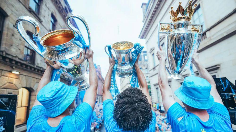 Pemain Manchester City menunjukkan tiga trofi juara kepada penggemar mereka. (mancity.com)