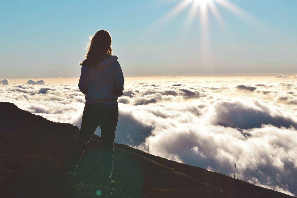ilustrasi wanita berdiri di gunung dan menatap awan (pexels.com/Tim Gouw)