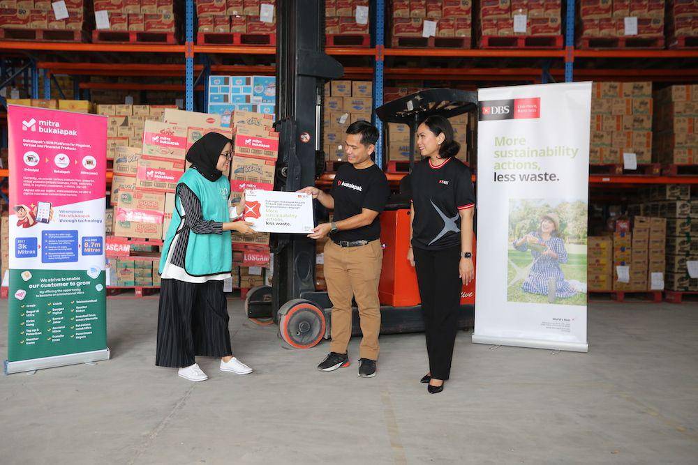 VP of Mitra FMCG & Fresh Bukalapak, Caesario Parlindungan (tengah) dan Head of Group Strategic Marketing & Communications PT Bank DBS Indonesia, Mona Monika (kanan) menyerahkan sumbangan produk makanan dan minuman instan kepada Executive Director Yayasan Surplus Peduli Pangan, Alya Fatina Diandari (Kiri) pada program “More Sustainability Actions, Less Waste“ di Tangerang. (Dok. Bank DBS Indonesia)