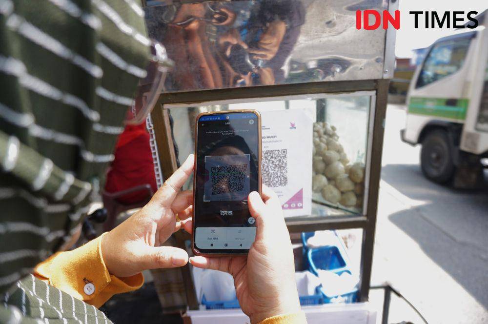 Seorang pembeli menggunakan QRIS untuk membeli bakso dagangan Mukti (IDN Times/Doni Hermawan)