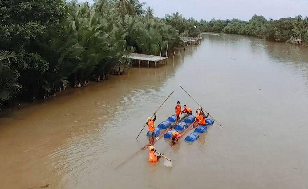 Perjuangan petugas PLN memobilisasi tiang melewati sungai ke Desa Akkotengeng, Kabupaten Wajo menggunakan rakit buatan. (Dok. PLN UID Sulselrabar)