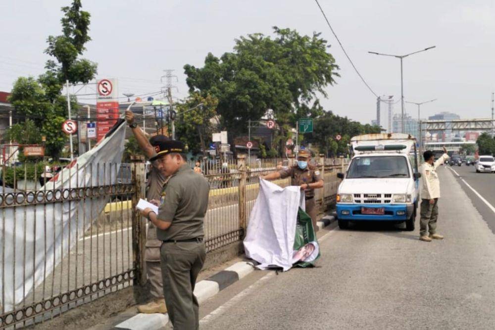 Satpol PP DKI Jakarta lepas spanduk kampanye. (dok. Satpol PP)