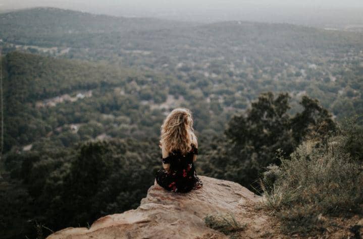 ilustrasi wanita sedang duduk melamun di atas bukit (unsplash.com/Hannah Busing)