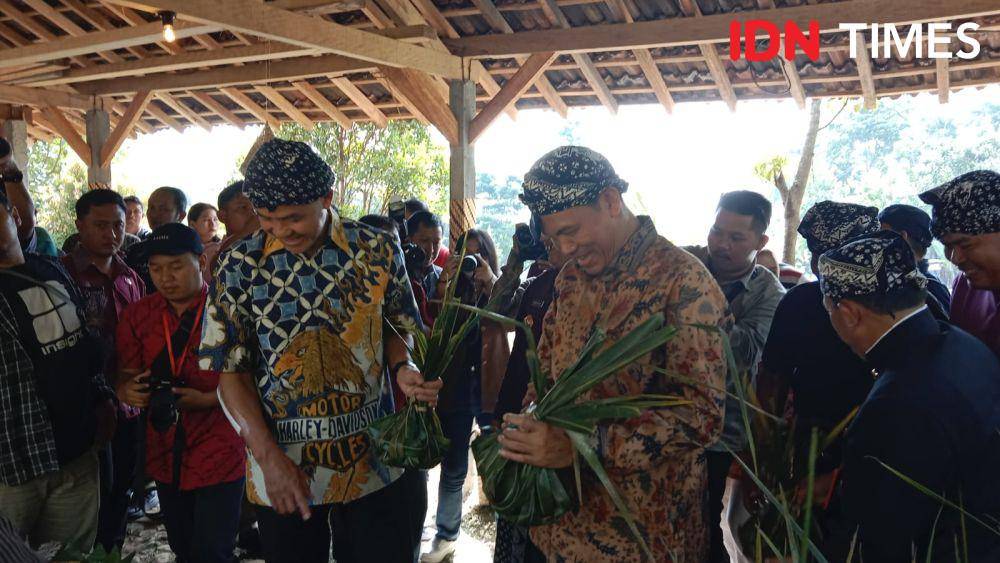 Gubernur Jateng Ganjar Pranowo dan Wali Kota Pariaman Genius Umar saat mengambil makanan yang dibungkus daun jati. (IDN Times/Fariz Fardianto)