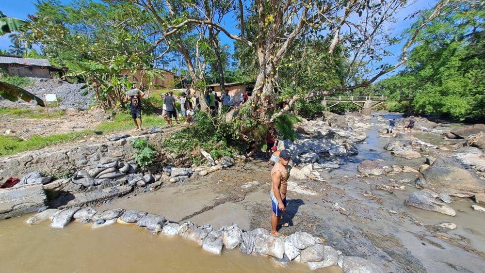 Seorang pria bertubuh kekar terlihat membantu tim SAR gabungan saat membendung aliran sungai memakai karung pasir. (IDN Times/Dok Humas Basarnas Cilacap)