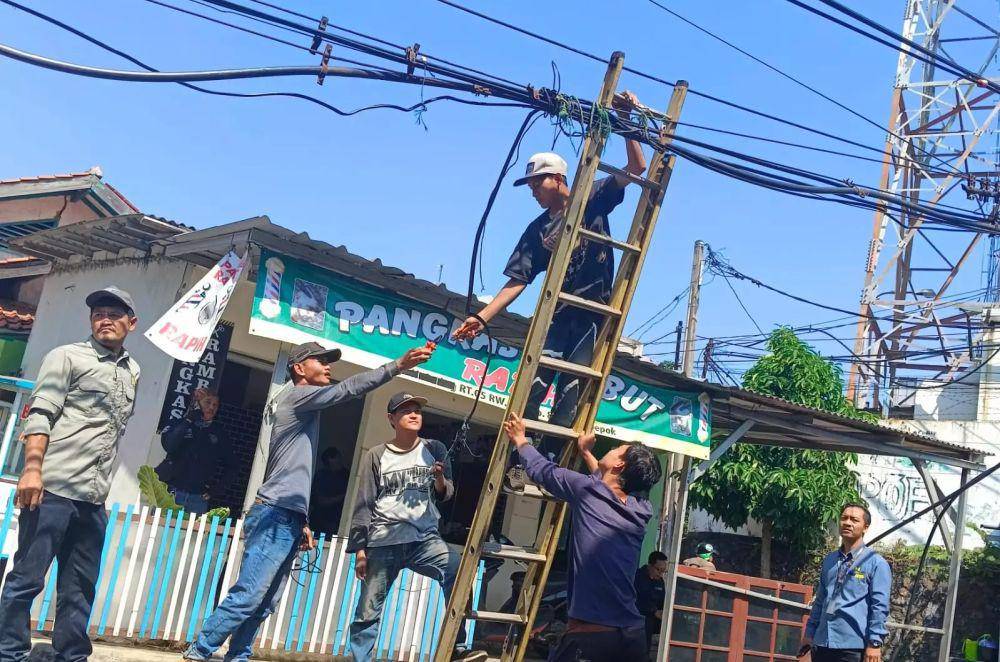 Petugas DPUPR Kota Depok melakukan penanganan kabel yang menjutai di jalan. (Istimewa)