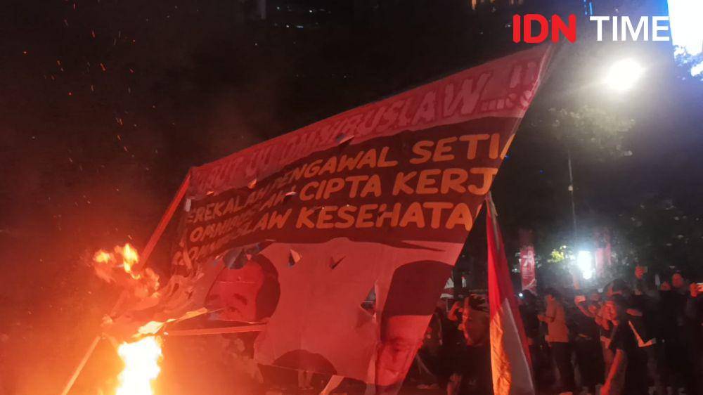 Massa buruh membakar baliho bergambar Presiden Joko "Jokowi" Widodo di Patung Kuda Arjuna Wiwaha atau depan Monumen Nasional (Monas), Jakarta Pusat, Kamis (10/8/2023). (IDN Times/Dini Suciatiningrum)