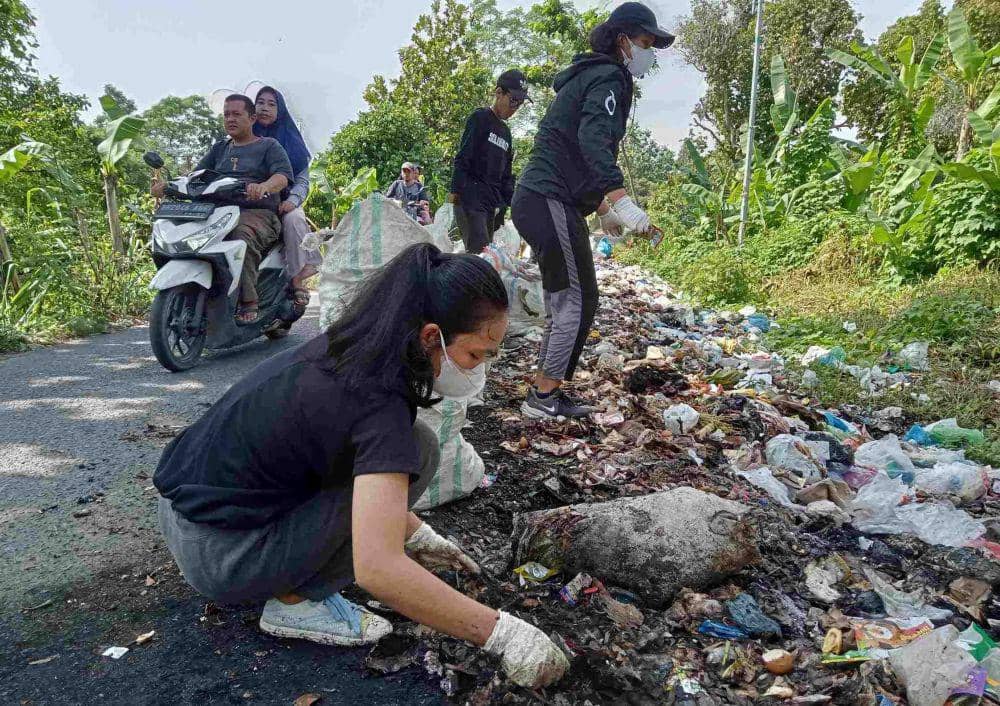 Beberapa volunteer sedang membersihkan sampah di pinggir Jalan Duku Raya, Desa Bandar Khalipah (IDN Times/Taufik Syahputra)