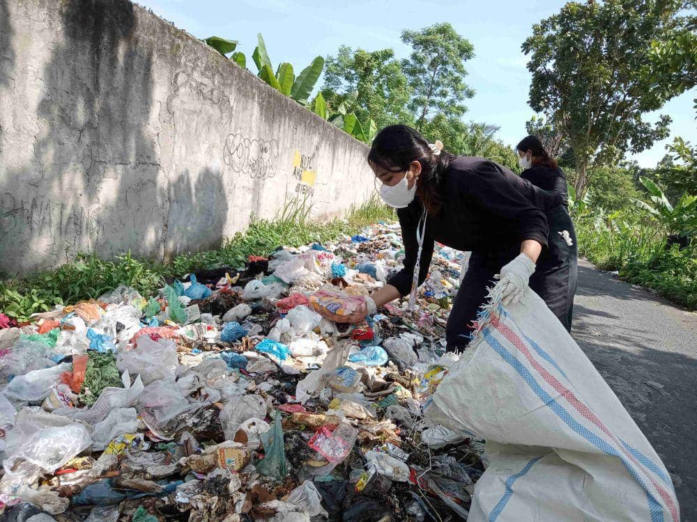 Volunteer sedang mengutip sampah di pinggir Jalan Dulu Raya, Desa Bandar Khalipah (IDN Times/Taufik Syahputra)