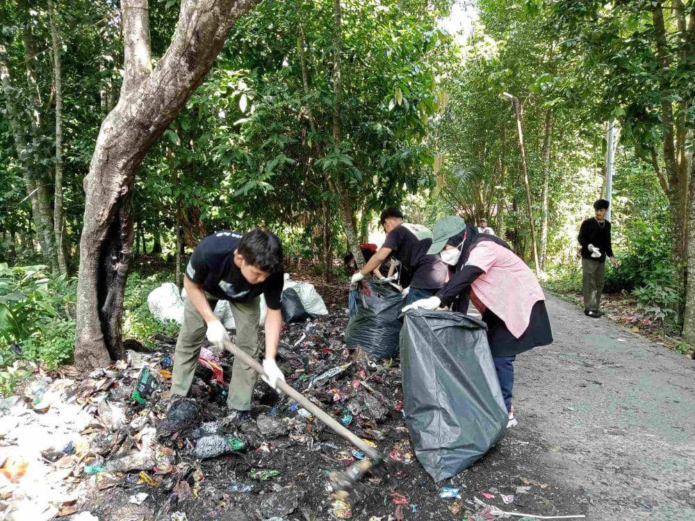 Beberapa volunteer sedang mengumpulkan sampah di pinggir Jalan Dulu Raya, Desa Bandar Khalipah (IDN Times/Taufik Syahputra)