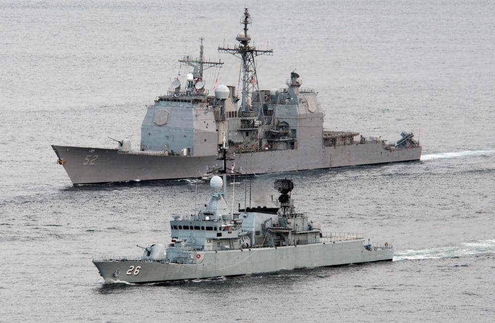 potret kapal penjelajah Ticonderoga class-USS Bunker Hill (CG-52) yang berada di belakang kapal korvet AL Malaysia KD Lekir (F26) dalam sebuah passing exercise di Selat Malaka (commons.wikimedia.org/James R. Evans)