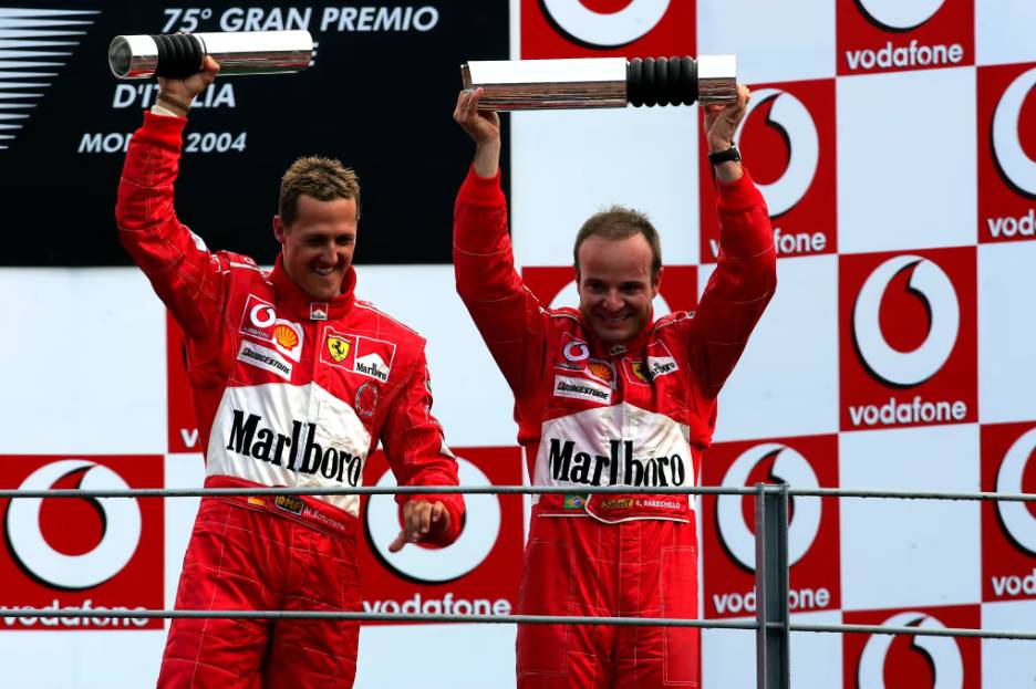 Rubens Barrichello (kanan) menjuarai GP Italia 2004 ditemani Michael Schumacher (kiri) yang finis kedua, memberikan kemenangan 1-2 untuk Ferrari. (formula1.com)