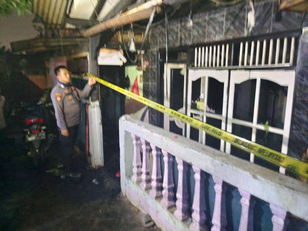 Polisi memasang garis polisi di rumah yang menewaskan pasutri pada peristiwa kebakaran di Jalan Dadap, Sukmajaya, Kota Depok. (Istimewa)