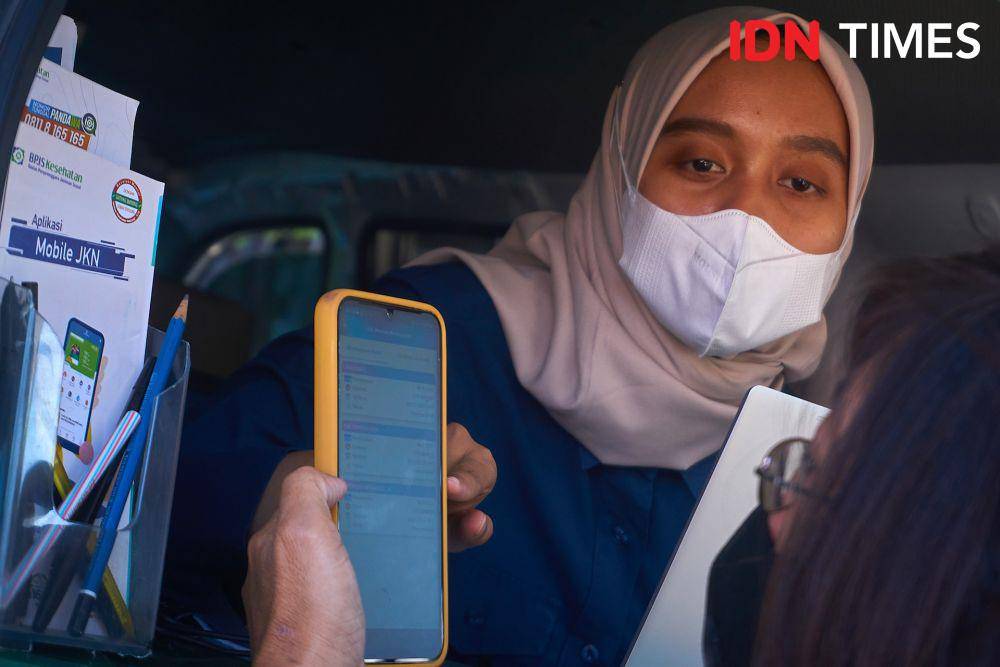 Petugas BPJS Kesehatan memandu warga yang memanfaatkan layanan BPJS Keliling untuk penggunaan aplikasi mobile Jaminan Kesehatan Nasional (JKN) di kawasan Dispendukcapil Semarang, Kamis (20/7/2023). (IDN Times/Dhana Kencana)