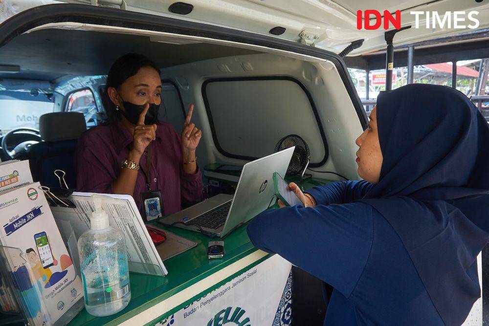 Petugas BPJS Kesehatan, Anita memberikan informasi kepada warga yang memanfaatkan layanan BPJS Keliling saat mengurus pendaftaran Program Jaminan Kesehatan Nasional (JKN) di kawasan Pasar Tradisional Johar Semarang, Jumat (14/7/2023). (IDN Times/Dhana Kencana)