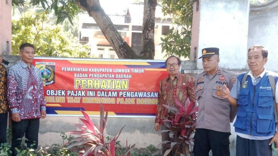 Kepala Dispenda Lotim, Muksin memasang spanduk peringatan di restoran yang tidak  taat bayar pajak (dok. Aming Dispenda Lotim)