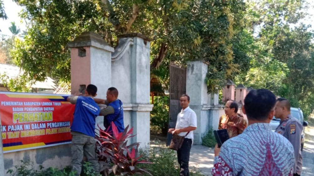 Petugas Dispenda Lotim memasang spanduk peringatan di restoran yang tidak  taat bayar pajak (dok. Aming/Dispenda Lotim)