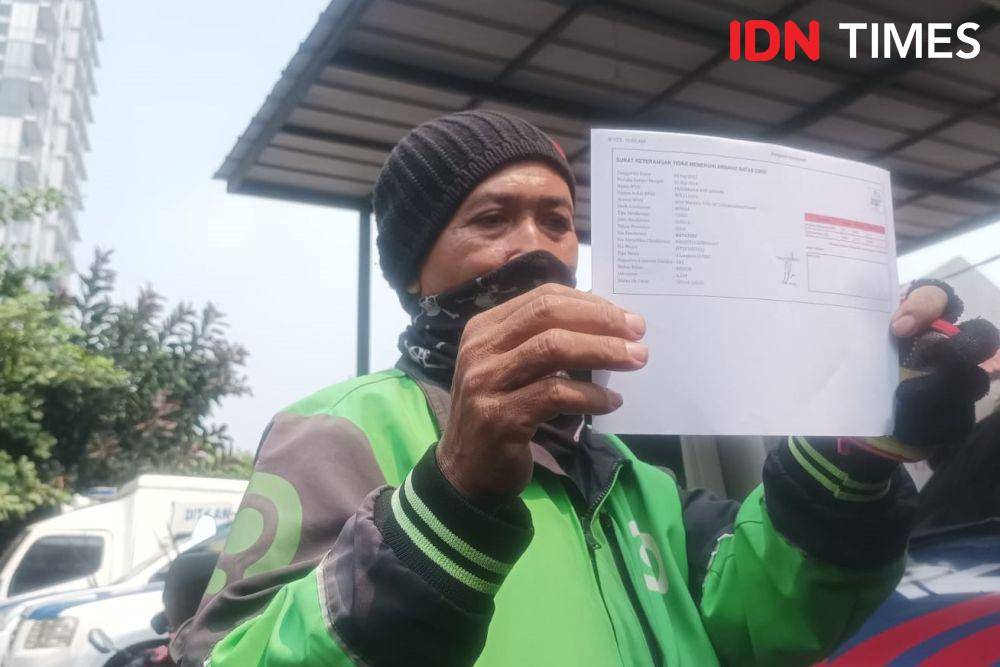 Pengemudi Ojol, Suwarna menunjukan surat tidak lulus emisi dan tilang di Dirlantas Polda Metro Jaya, Jumat (1/9/2023). (IDN Times/Dini Suciatiningrum)