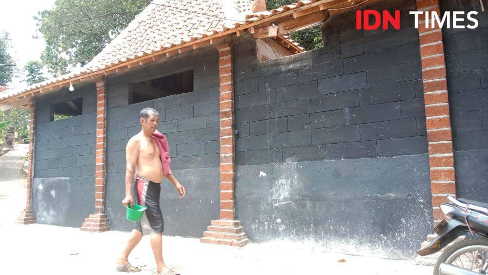 Seorang pria paruh baya warga RT 05 Kampung Kandri Gunungpati Semarang berjalan sambil menenteng peralatan mandi menuju bilik pemandian umum di Sendang Gede. (IDN Times/Fariz Fardianto)