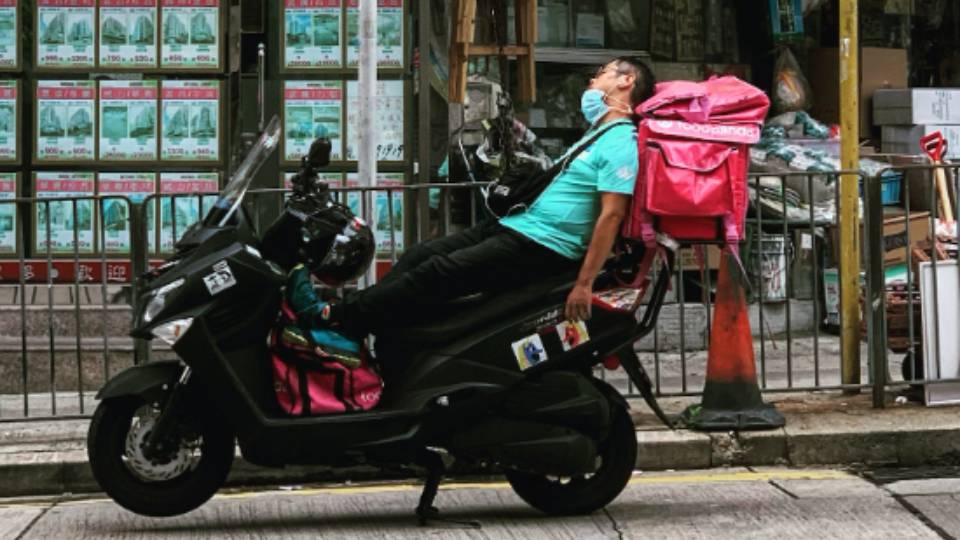 Ilustrasi kurir sedang tidur di atas motornya (unsplash.com/Julian Tong)